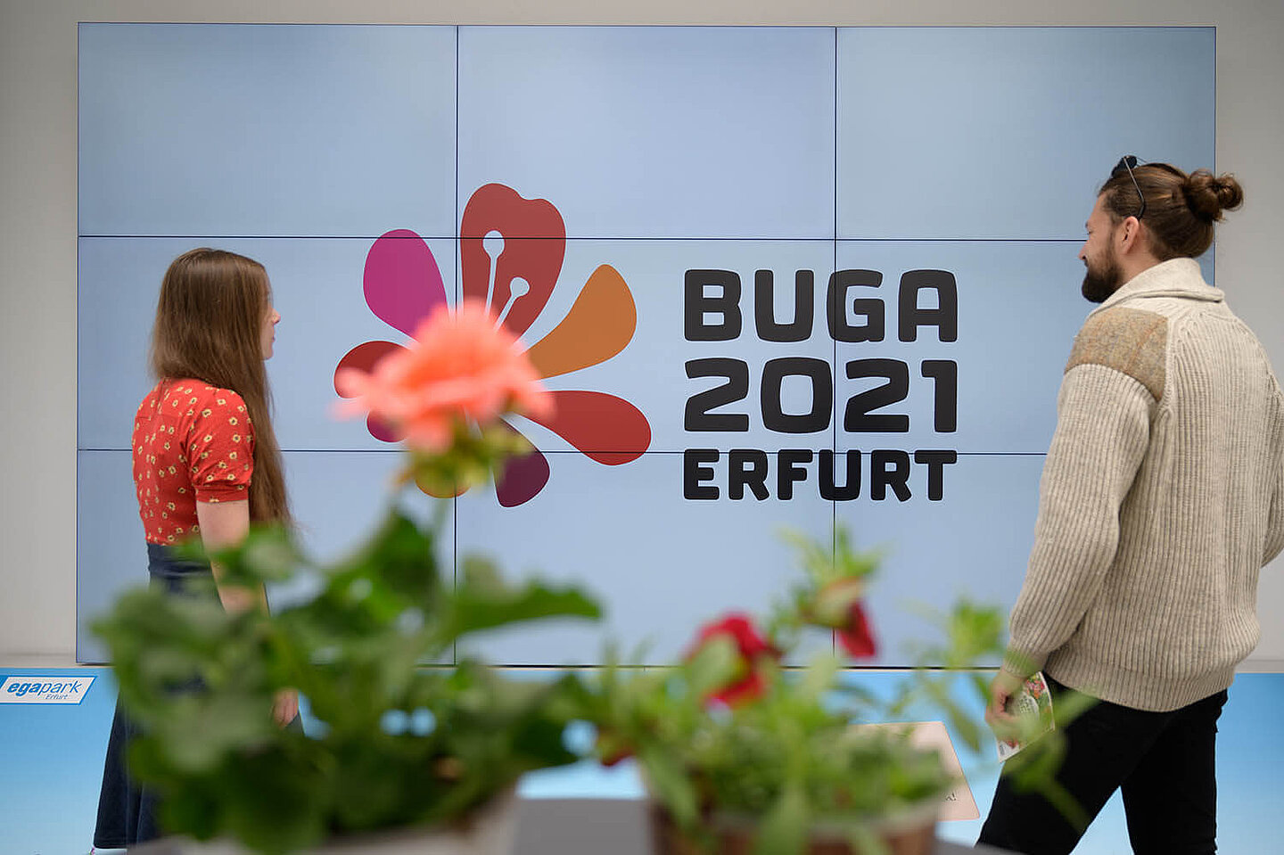 ein Mann und eine Frau welche sich das Logo der BUGA 2021 in Erfurt ansehen
