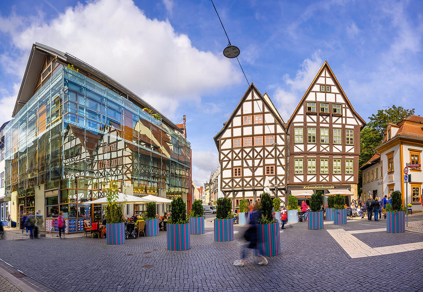 A modern and two old half-timbered houses on the Krämerbrücke, in front of which are planted flower pots