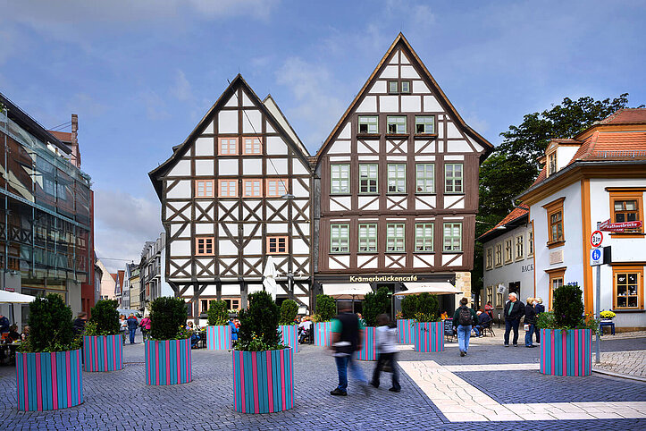 Zwei alte Fachwerkhäuser an der Krämerbrücke, vor denen bepflanzte Blumenkübel stehen