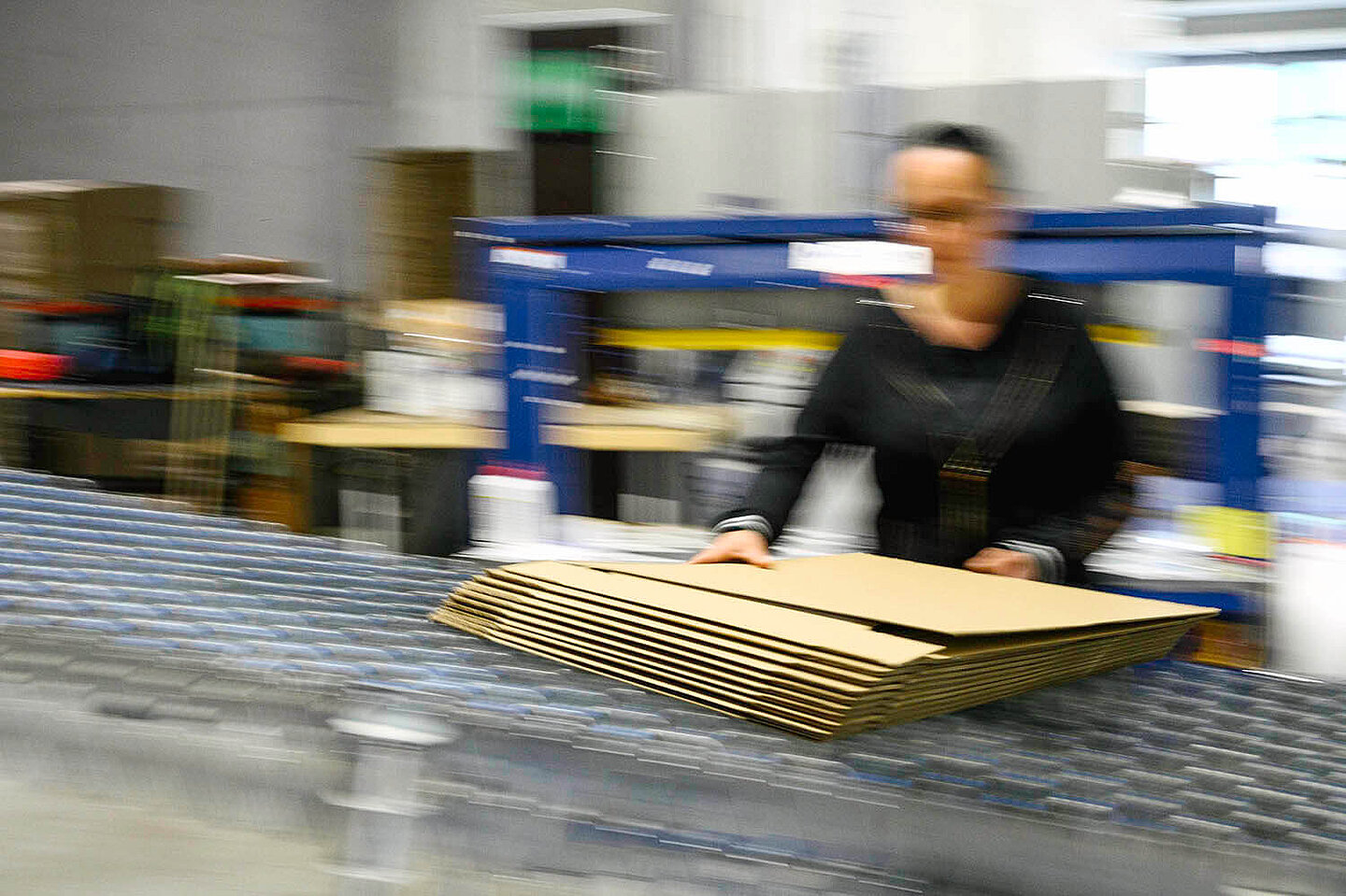 Eine am Fließband arbeitende Frau hält Verpackungen in der Hand