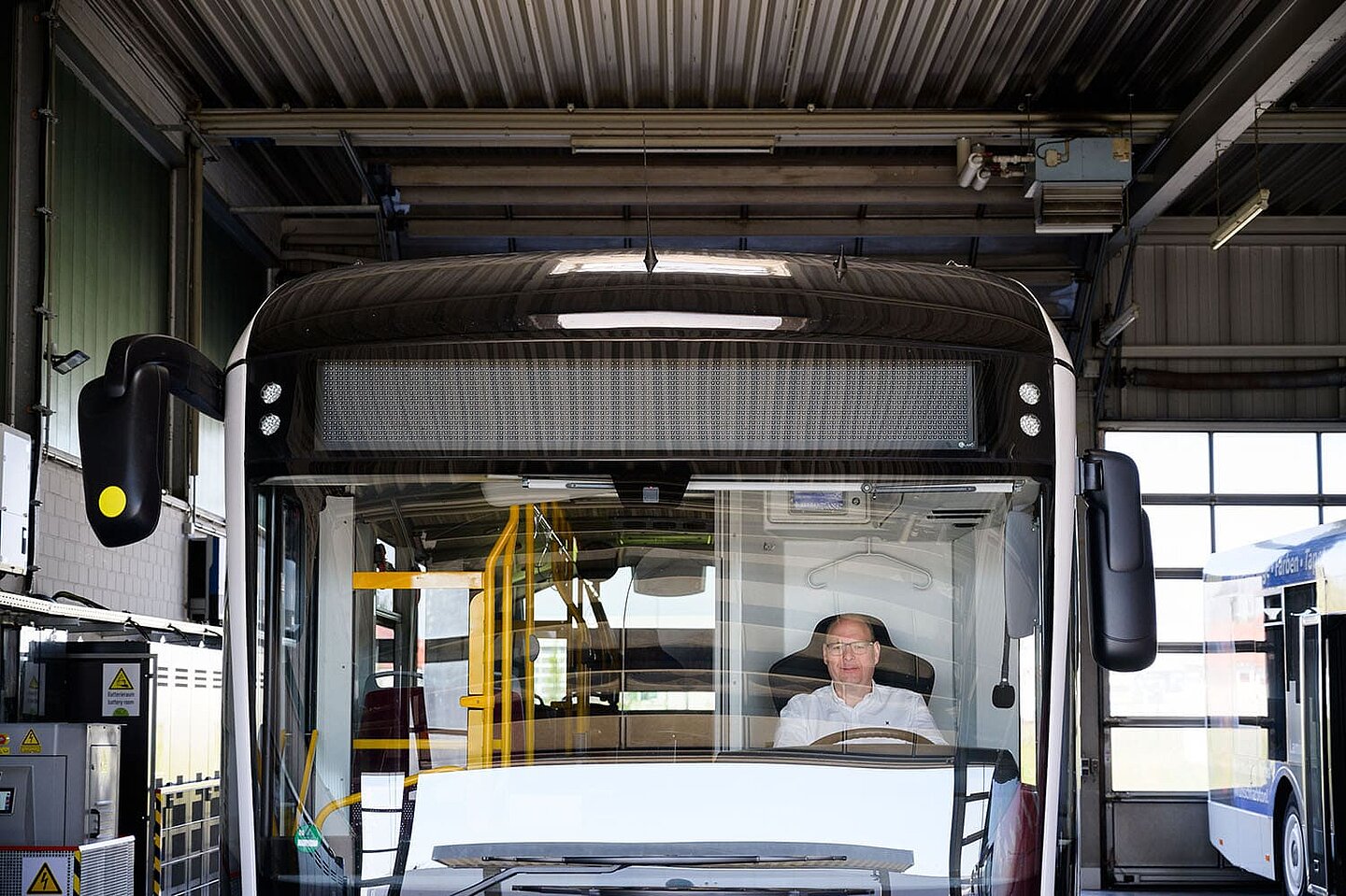 Ein Busfahrer sitzt in seinem in der Garage stehenden Bus